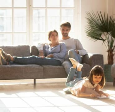 Happy parents relaxing on couch while kid drawing on floor